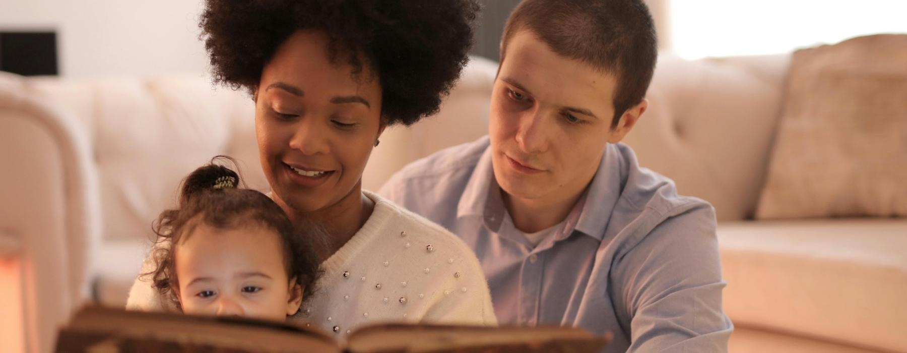 mother and father reading to their baby